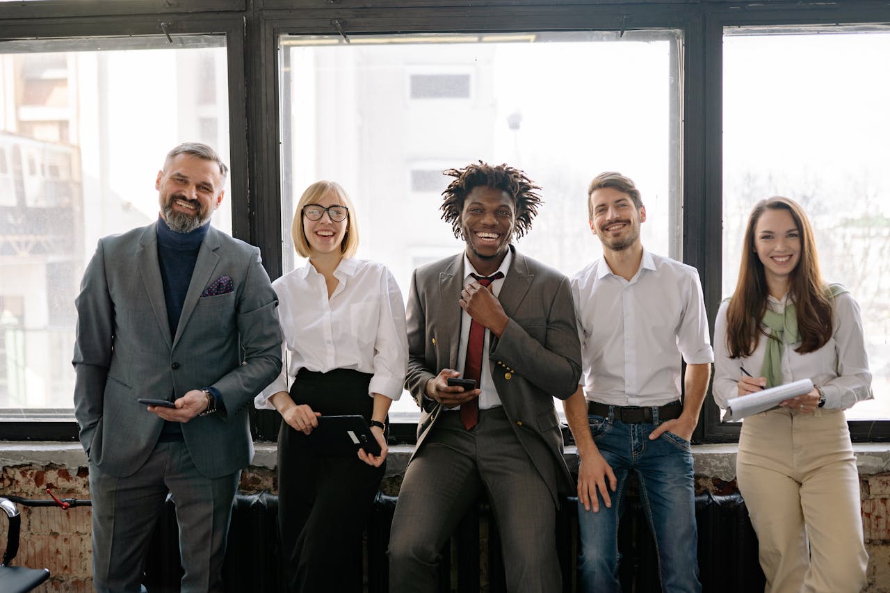 A diverse group of business professionals smiling and standing together in the office.